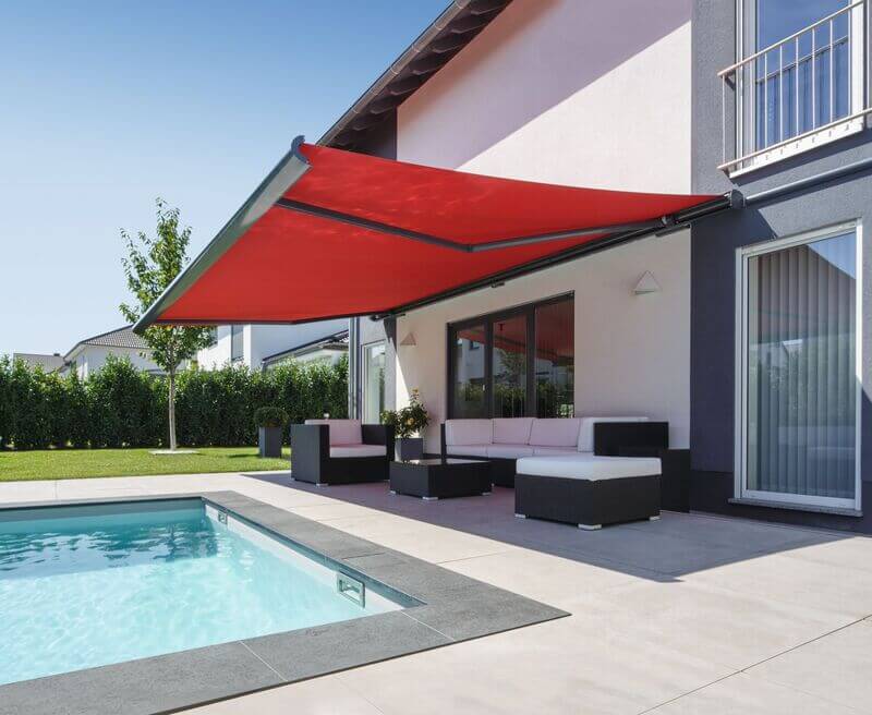 Une terrasse avec une piscine, un auvent rouge et des meubles élégants.