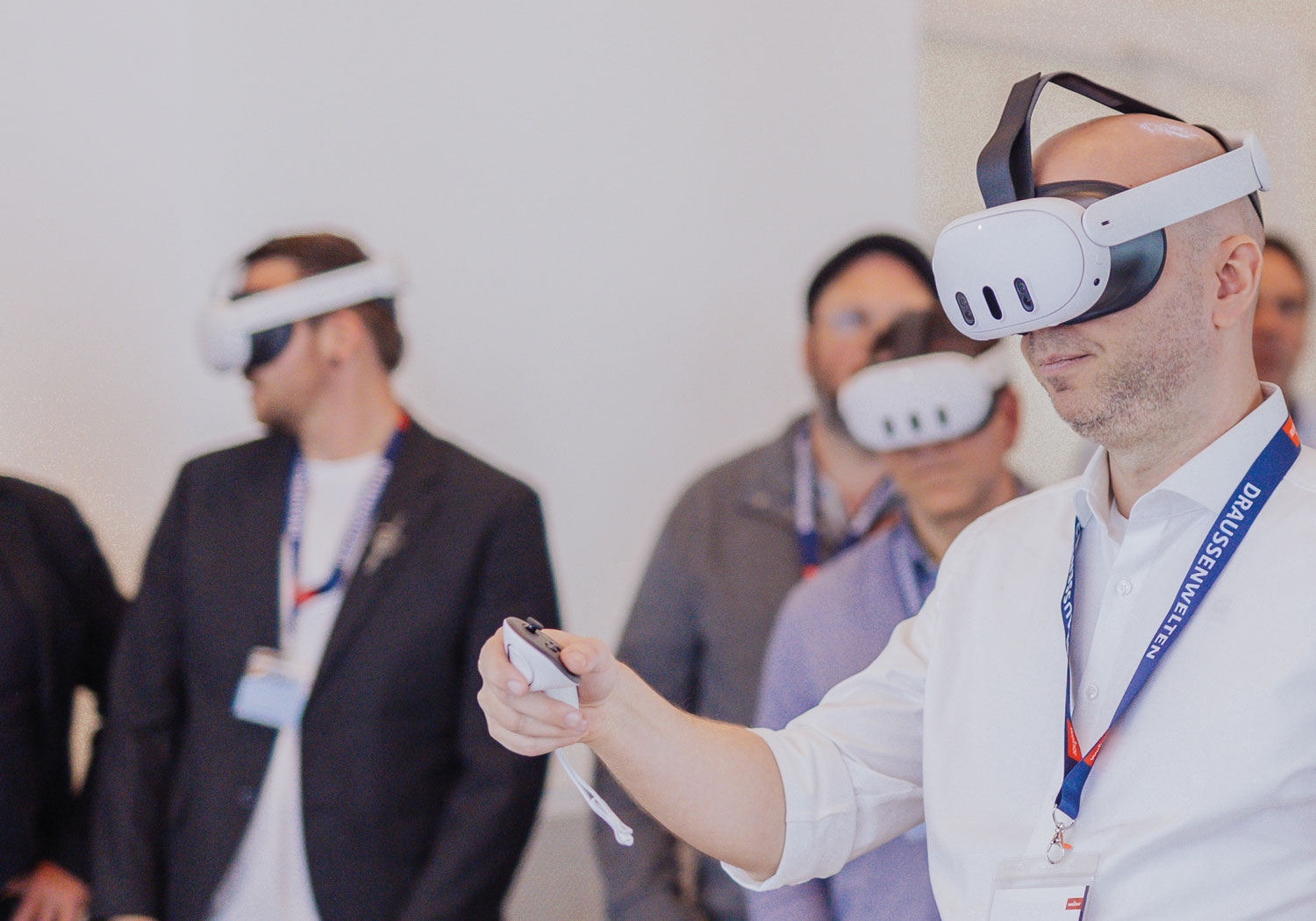Groupe de personnes portant des casques de réalité virtuelle, un homme en avant-plan interagissant avec un dispositif.