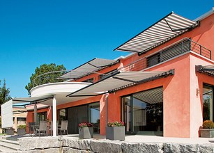 Maison moderne avec plusieurs auvents sur une terrasse, couleurs vives et lignes courbes. 