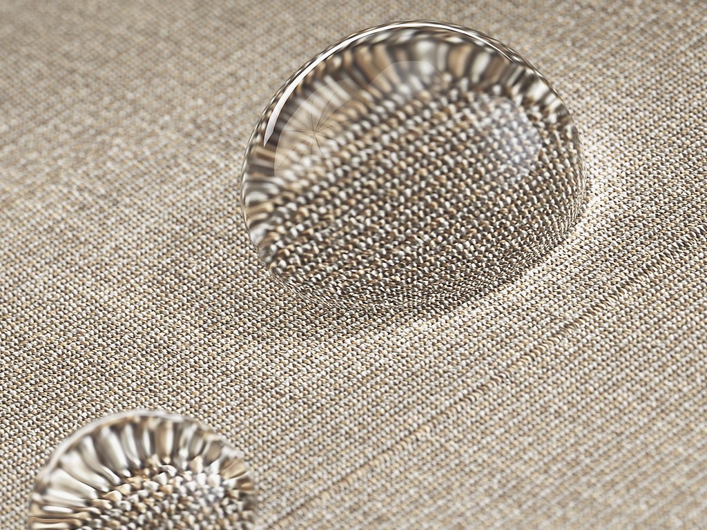 Gouttes d'eau sur un tissu beige avec texture visible.