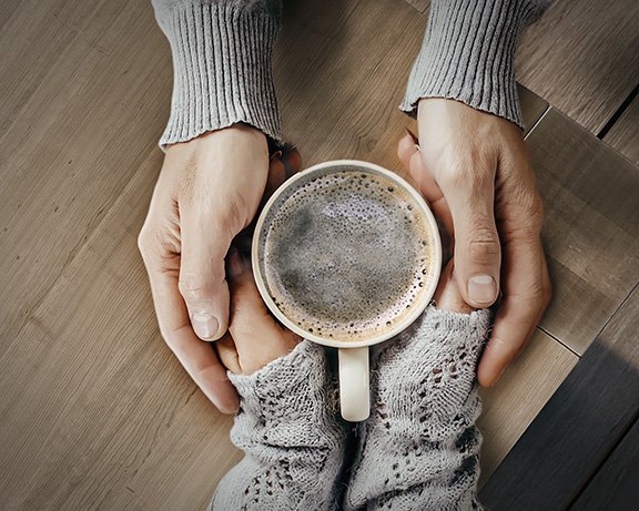 Deux mains tenant une tasse de café sur une table en bois. Deux mains tenant une tasse de café sur une table en bois.