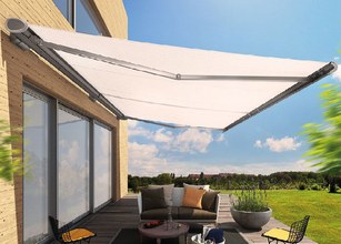 Une marquise blanche déployée au-dessus d'une terrasse avec un canapé et une vue sur un jardin verdoyant. 