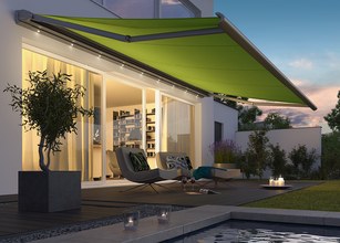 Vue d'une terrasse avec une grande store verte déployée, créant un espace ombragé. 