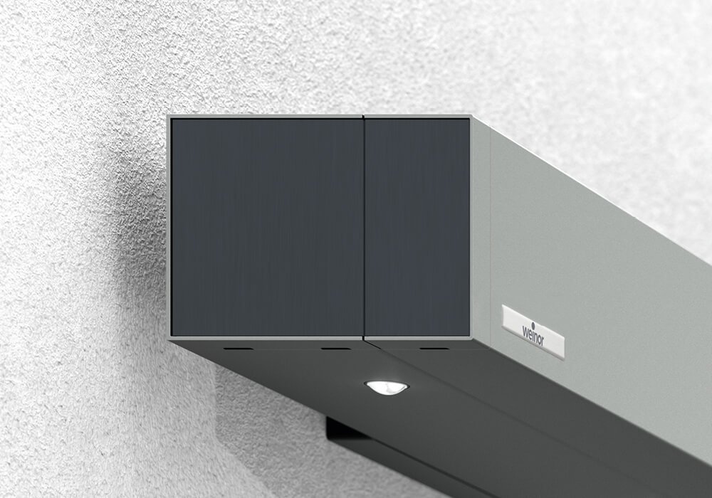Store de terrasse Smaila avec cassette cubique, couleur de la structure gris bleuté, monté sur une façade moderne