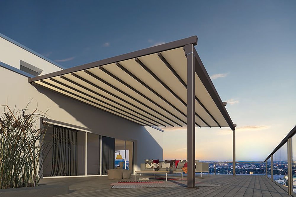 Terrasse avec une grande surstructure en aluminium et un toile de store, vue sur la ville au coucher du soleil.