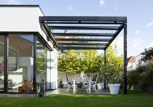 Terrassensituation avec une surdachung noire, des murs en verre et un aménagement verdoyant.