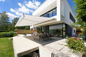 Terrasse moderne avec une surbrillance blanc, un auvent et des sièges autour d'une table. Ciel bleu et nuages.