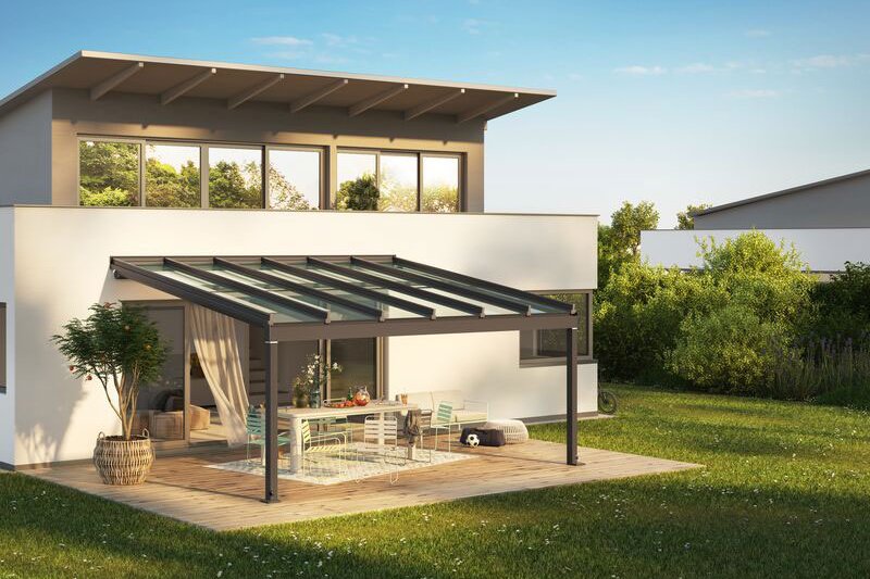 Maison moderne avec une terrasse, une structure de verre et un espace de vie extérieur, entourée de verdure. Maison moderne avec une terrasse, une structure de verre et un espace de vie extérieur, entourée de verdure.