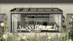 Maison moderne avec terrasse couverte et fenêtres en verre, entourée de verdure.