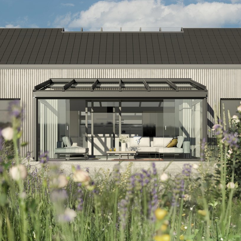 Maison moderne avec terrasse couverte et fenêtres en verre, entourée de verdure.