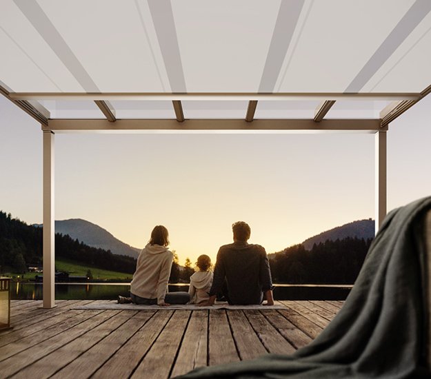 Famille profitant d'un coucher de soleil sous une structure avec un toit clair et un environnement naturel. 