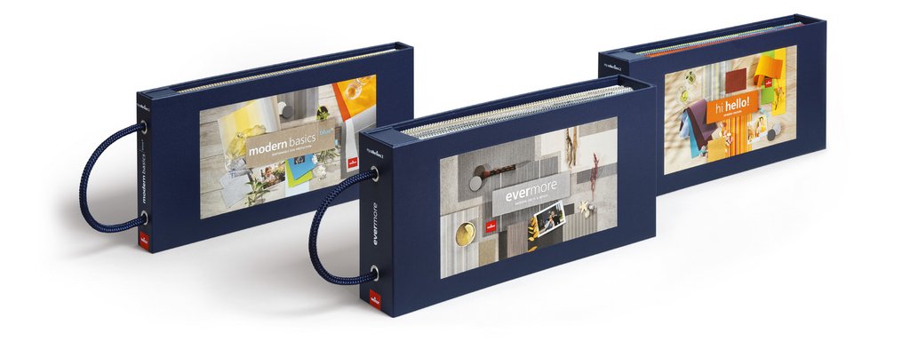 Trois boîtes rectangulaires de couleur bleu navy, avec des motifs colorés sur la façade. Trois boîtes rectangulaires de couleur bleu navy, avec des motifs colorés sur la façade.