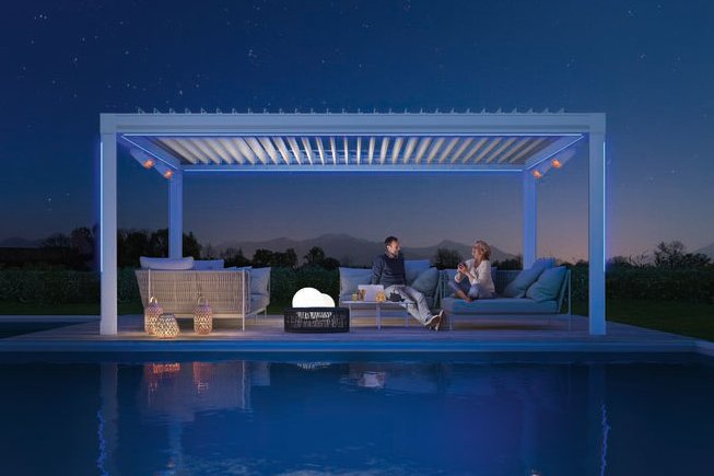 Ensemble de terrasse avec une surélévation, éclairage et des personnes assises près d'une piscine sous un ciel étoilé. Ensemble de terrasse avec une surélévation, éclairage et des personnes assises près d'une piscine sous un ciel étoilé.