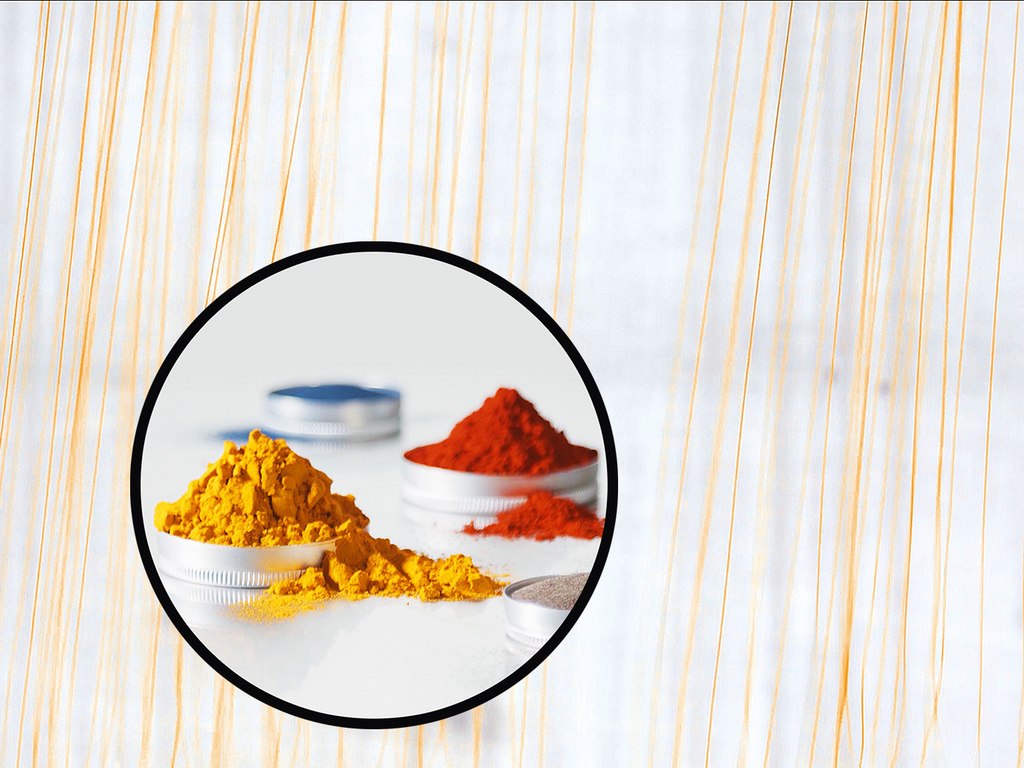 Des épices en poudre de couleurs vives, principalement jaune et rouge, dans des récipients.