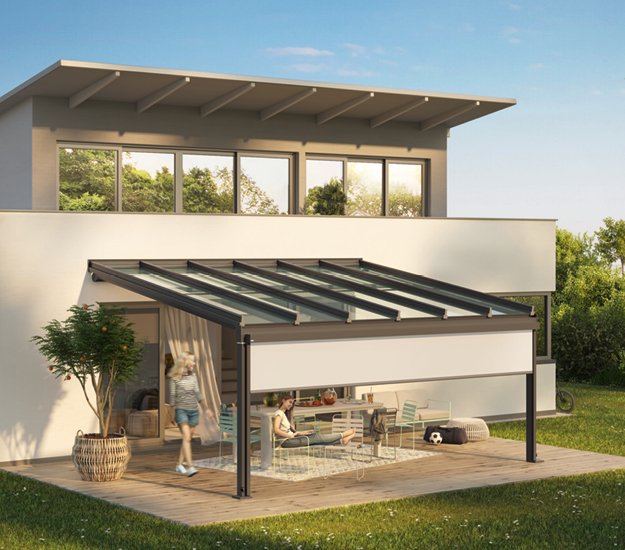 Une terrasse avec une surcouche à structure noire et un toit en verre, entourée de verdure. 
