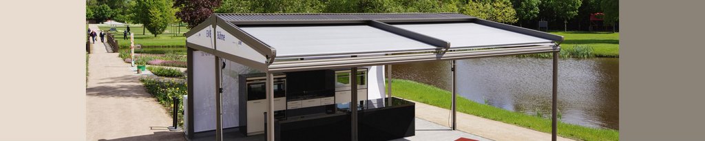 Une structure de protection avec toit en toile, située près d'une promenade et d'un plan d'eau. Une structure de protection avec toit en toile, située près d'une promenade et d'un plan d'eau.