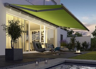 Marquise verte déployée au-dessus d'une terrasse contemporaine, avec des meubles modernes et un environnement extérieur. 