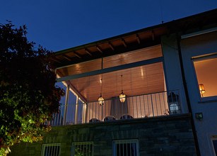 Terrasse éclairée la nuit avec des lanternes suspendues et une structure moderne. 